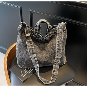 Detail of vintage washed black denim tote bag with adjustable strap on a chair