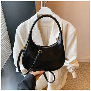 Close-up of black crescent leather bag with gold zipper and adjustable shoulder strap