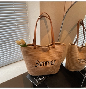 Close-up of a large straw tote bag featuring Summer embroidery and leather handles