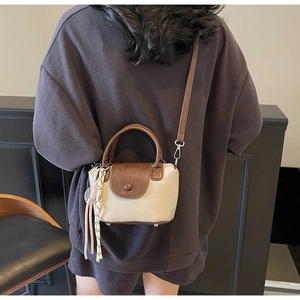 Detail of a vintage mini crossbody bag with beige canvas and brown leather straps