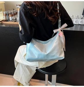 Close-up of light blue hobo bag with lace bow and pink heart charm detail