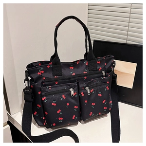 Détail du sac cabas noir à imprimé cerise avec deux poches zippées et bandoulière réglable