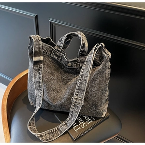 Detail of vintage denim tote bag showing the wide shoulder strap and metal buckle