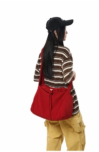 Détail du sac bandoulière rouge avec cordon de serrage et large bandoulière ajustable