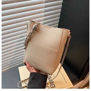 Close-up of off-white bucket bag with lychee texture and silver metal chain strap