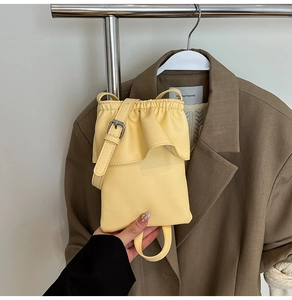 Détail du sac bandoulière jaune à motif litchi avec rabat plissé et fine bandoulière