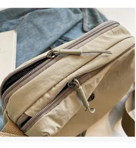 Close-up of dual-layer smooth zipper design on a beige multi-layer nylon crossbody bag