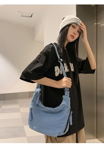 Close-up of light blue canvas crescent bag with wide adjustable shoulder strap on model