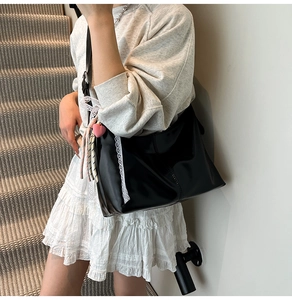 Detail of black dumpling shoulder bag featuring white lace ribbon and pink heart charm