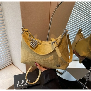 Close-up of yellow pebble leather dumpling bag with heart pendant and silver logo