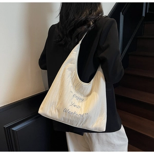 Macro detail of quilted ivory canvas tote bag featuring Enjoy Your Weekend blue embroidery