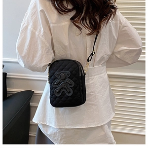 Quilted black mini phone bag with sequin bear worn as crossbody on white shirt