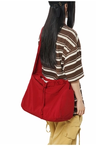 Détail du grand sac à bandoulière rouge avec cordon de serrage porté par un modèle