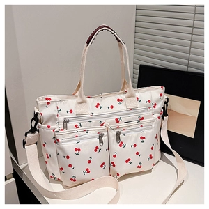 Détail du cabas en toile blanche avec imprimé cerise et multiples poches zippées devant