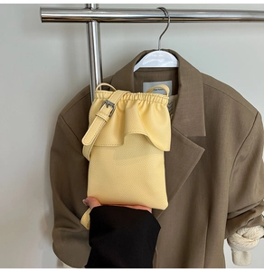 Gros plan sur un sac seau jaune vif en cuir litchi avec des plis élégants