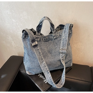 Close-up of vintage denim tote bag with metal buckle and washed canvas texture on leather