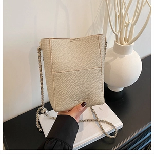 Detail of cream bucket bag showing lychee pattern leather and gold ball chain adjuster