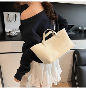 Detail shot of the cream bucket bag showing smooth texture and cylindrical handle