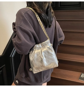 Détail du sac seau argenté matelassé avec finition métallique et bandoulière chaîne