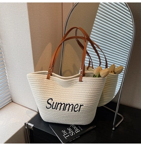 Détail d'un sac cabas tissé crème avec broderie Summer noire et des anses en cuir marron