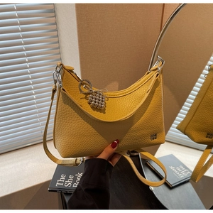 Detail view of bright yellow litchi pattern leather bag with silver metal branding logo