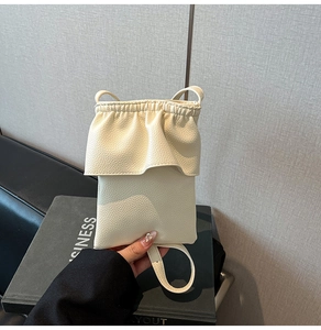 Détail de la texture cuir grainé crème et du design plissé sur le dessus du sac à main