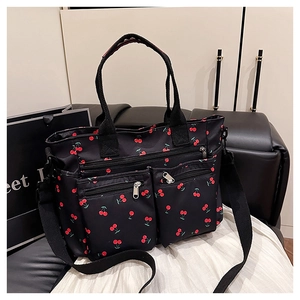 Détail d'un sac cabas en nylon noir avec imprimés cerises et deux poches zippées