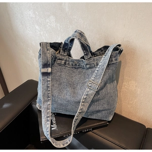 Close-up of blue washed denim tote bag with adjustable shoulder strap and metal hardware