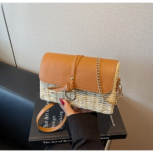 Detailansicht der gewebten Stroh- und Ledertasche mit goldener Kettenriemen-Optik