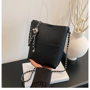 Close-up of black lychee grain leather bucket bag with silver chain and ball slider