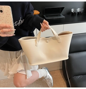 Close-up of premium cream bucket bag with dual handles and elegant snap closure detail