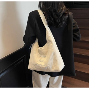 Detail of cream white pleated tote bag with Enjoy Your Weekend blue embroidery text