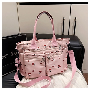 Détail d'un sac cabas rose à imprimé cerises avec trois poches zippées et bandoulière