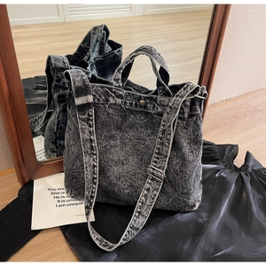Detail of acid wash denim tote bag with adjustable shoulder strap and sturdy handles