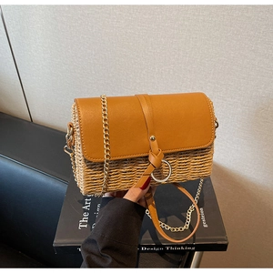 Detail of hand-woven straw crossbody bag with caramel leather flap and gold chain strap