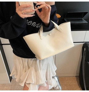 Detail of minimalist off-white leather tote bag shown in a professional office setting