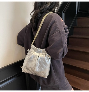 Detail of silver quilted bucket bag with chain strap shown on a model's shoulder