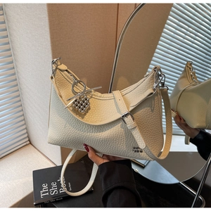 Close-up of beige lychee grain leather handbag with silver heart pendant detail