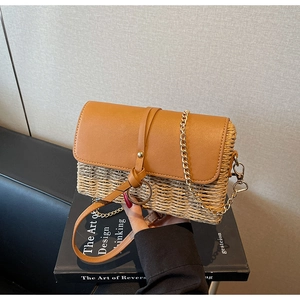Detail showing woven texture and brown leather flap with golden chain strap on shoulder bag