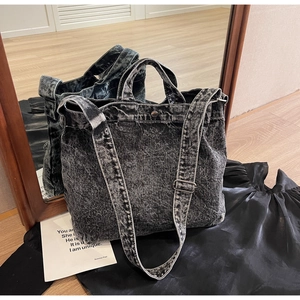 Detail view of black washed denim tote bag with adjustable shoulder strap and metal rivets