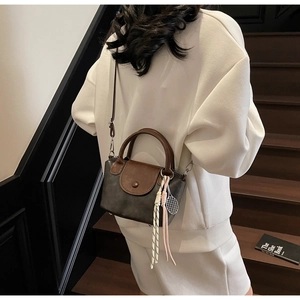 Detailed back view of a mini two-tone crossbody bag with woven tennis racket charm detail