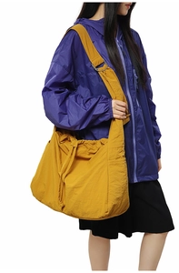 Gros plan du sac bandoulière jaune en nylon avec cordon et coupe-vent violet pour femme