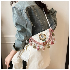 Detailed close-up of bohemian knit shoulder bag with colorful embroidery and tassels