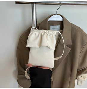 Gros plan d'un sac bandoulière crème avec détails volantés et cuir à grain galet