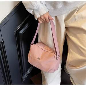 Vue détaillée du sac bandoulière rose en nylon avec large sangle et logo métallique