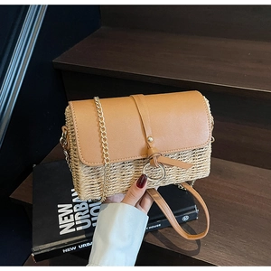 Detail of straw shoulder bag featuring caramel leather flap and golden metal ring buckle