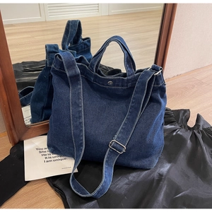 Detail of blue denim tote bag showing metal strap buckle and snap button closure