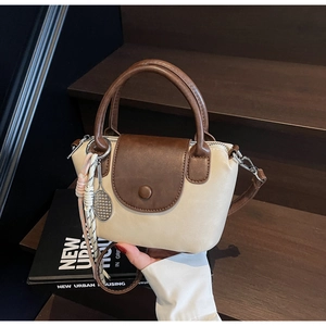 Close-up of cream and brown crossbody bag featuring tennis racket charm and tassel details