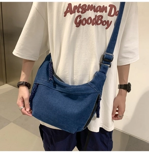 Detail of blue denim hobo bag featuring white contrast stitching and adjustable strap