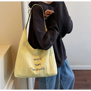 Detail of a cream canvas tote bag with Enjoy Your Weekend text and pleated texture
